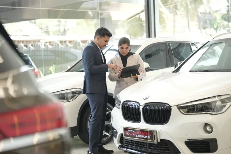 Manu's Car World team members reviewing car details in the showroom
